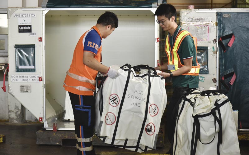 Two staff members moving fire containment bags containing dangerous goods shipments at a terminal