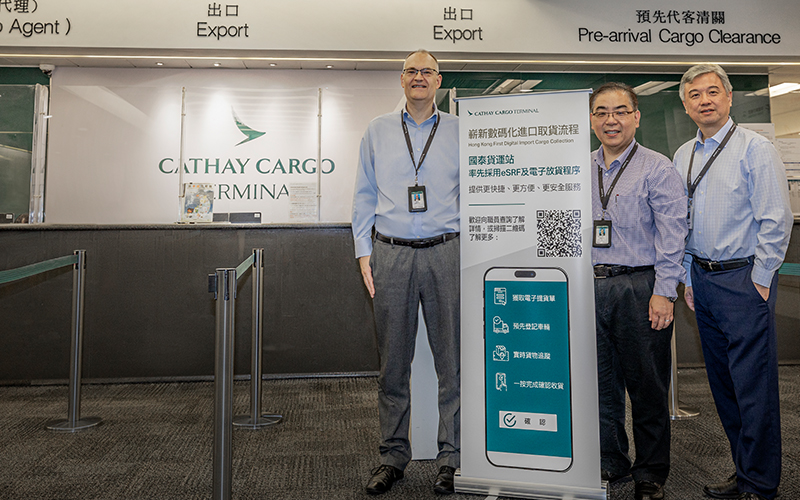 Cathay Cargo Terminal Chief Operating Officer Mark Watts and his team in the import and export office with a sign encouraging take up of the new app